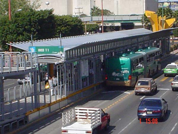 The photo shows an articulated bus docking at a Bus Rapid Transit station in León, Mexico.
