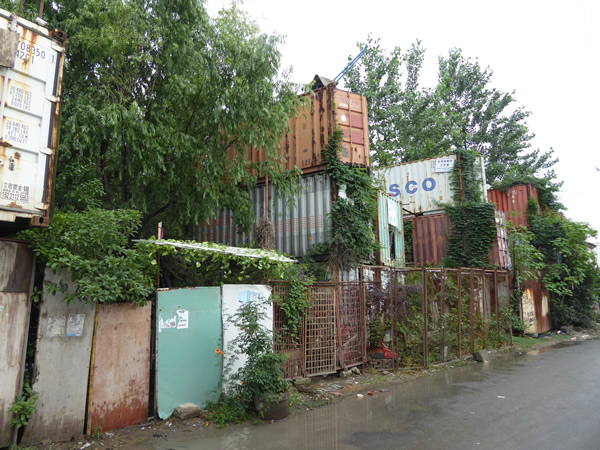 Abandoned shipping containers located near the waterfront (and one of the city’s refuse dumps) are commandeered by those without shelter who have transformed the steel boxes into living units, complete with pirated electricity in Shanghai, China.  Photo by Benjamin Clavan, 2015.
